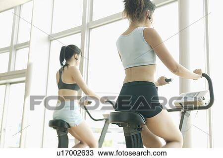 Two young women perform exercise in a well equipped gym View Large Photo Image Stock Image - Two young women perform exercise in a well equipped gym. Fotosearch