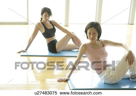 Two young women performing floor exercise in the gym View Large Photo Image Stock Photography - Two young women performing floor exercise in the gym. Fotosearch
