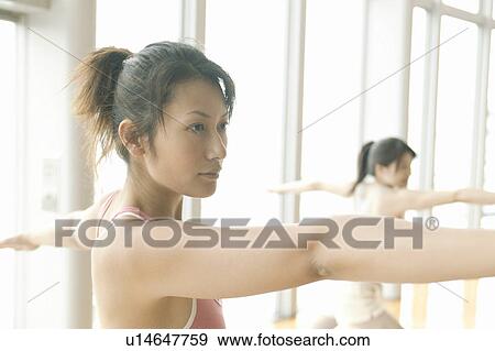 Two young women stretch their arms while exercising in the gym View Large Photo Image Stock Photo - Two young women stretch their arms while exercising in the gym. Fotosearch