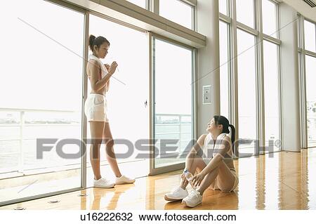 Two young women take a break from exercise as they relax near the sliding door View Large Photo Image Stock Image - Two young women take a break from exercise as they relax near the sliding door. Fotosearch