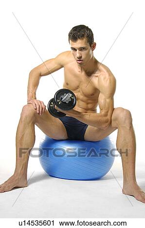 Portrait of a young man sitting on a fitness ball and exercising with a hand weight View Large Photo Image Stock Image - Portrait of a young man sitting on a fitness ball and exercising with a hand weight. Fotosearch