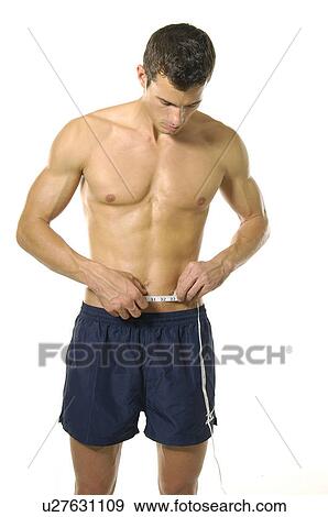 Stock Photo - Young man measuring his abdomen with a measuring tape. Fotosearch