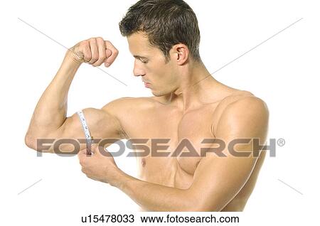 Stock Image - Young man measuring his biceps with a measuring tape. Fotosearch