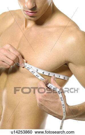 Stock Image - Close-up of a young man measuring his chest. Fotosearch