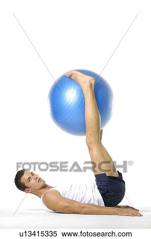 Stock Photography - Portrait of a young man exercising with a fitness ball. Fotosearch