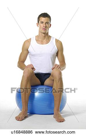 Portrait of a young man sitting on a fitness ball View Large Photo Image Stock Photograph - Portrait of a young man sitting on a fitness ball. Fotosearch