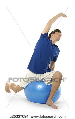 Young man sitting on a fitness ball and exercising View Large Photo Image Picture - Young man sitting on a fitness ball and exercising. Fotosearch