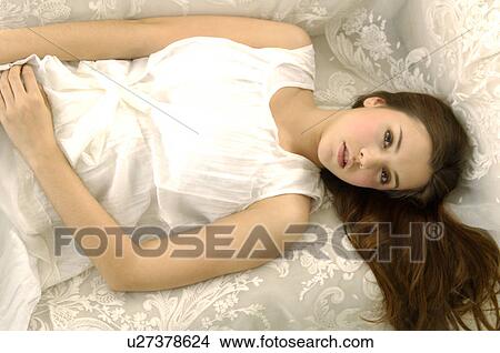 Portrait of a young woman lying on a couch View Large Photo Image Picture - Portrait of a young woman lying on a couch. Fotosearch