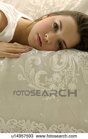 Stock Image - Portrait of a young woman lying on a couch. Fotosearch