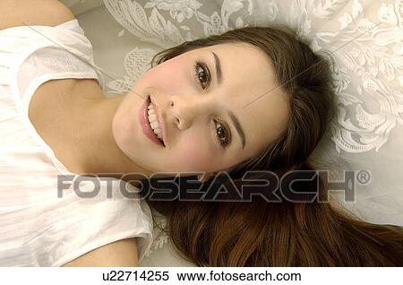 Stock Photography - Portrait of a young woman lying on a couch and smiling. Fotosearch