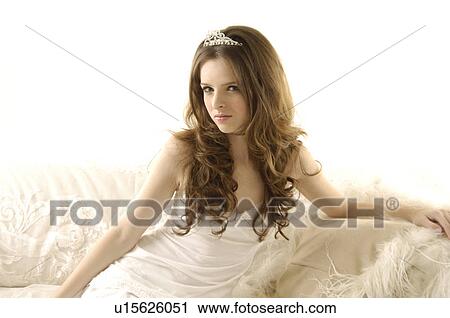 Portrait of a young woman sitting on a couch and wearing a tiara View Large Photo Image Stock Image - Portrait of a young woman sitting on a couch and wearing a tiara. Fotosearch