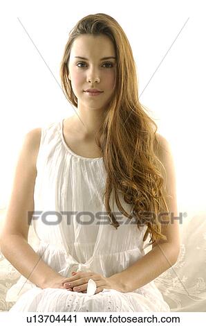 Stock Image - Portrait of a young woman sitting on a couch. Fotosearch