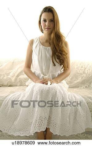 Stock Photo - Portrait of a young woman sitting on a couch. Fotosearch