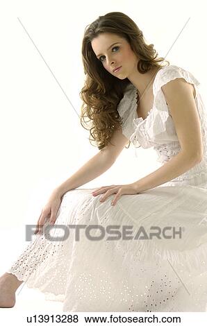 Stock Photo - Portrait of a young woman sitting with her hands on her knees. Fotosearch