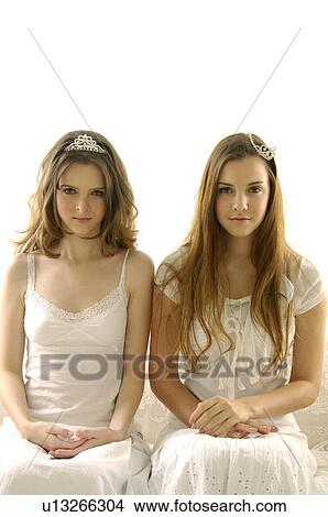 Picture - Portrait of two young women sitting on a couch. Fotosearch