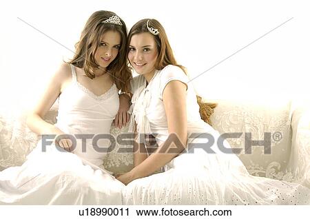Stock Image - Portrait of two young women wearing tiaras and smiling. Fotosearch