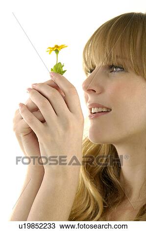 Close-up of a young woman holding a flower View Large Photo Image Stock Image - Close-up of a young woman holding a flower. Fotosearch