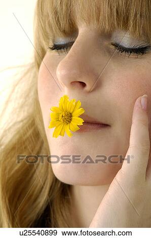 Close-up of a young woman holding a flower in her mouth View Large Photo Image Stock Photo - Close-up of a young woman holding a flower in her mouth. Fotosearch