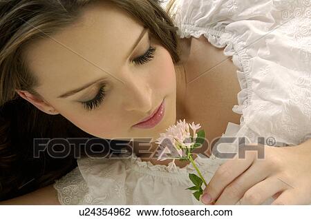 Close-up of a young woman smelling a flower View Large Photo Image Stock Image - Close-up of a young woman smelling a flower. Fotosearch