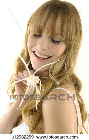 Close-up of a young woman smiling and holding a flower View Large Photo Image Stock Photo - Close-up of a young woman smiling and holding a flower. Fotosearch