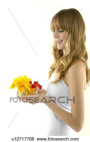 Stock Photo - Side profile of a young woman smiling and holding flowers. Fotosearch