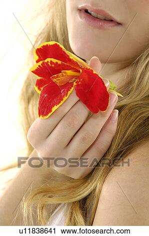 Stock Image - Close-up of a young woman holding a flower. Fotosearch