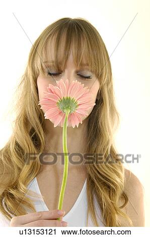 Stock Image - Close-up of a young woman smelling a flower. Fotosearch