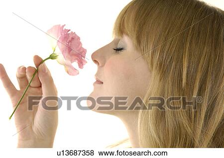 Stock Photo - Close-up of a young woman smelling a flower. Fotosearch
