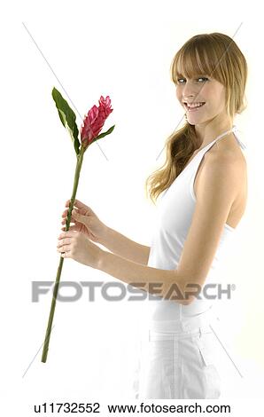 Stock Image - Portrait of a young woman holding a flower and smiling. Fotosearch
