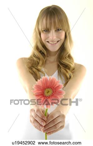 Stock Image - Portrait of a young woman holding a flower. Fotosearch