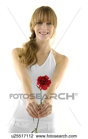 Stock Image - Portrait of a young woman holding a flower and smiling. Fotosearch