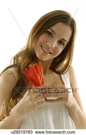 Stock Image - Portrait of a young woman holding a flower. Fotosearch