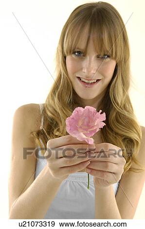 Stock Photo - Portrait of a young woman holding a flower. Fotosearch