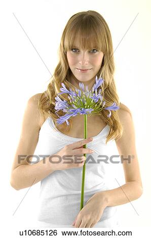 Portrait of a young woman holding a flower View Large Photo Image Stock Photograph - Portrait of a young woman holding a flower. Fotosearch
