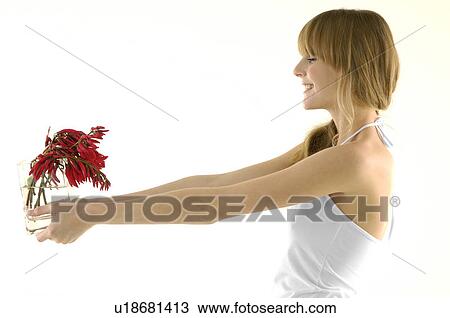 Stock Image - Side profile of a young woman holding a flower pot. Fotosearch