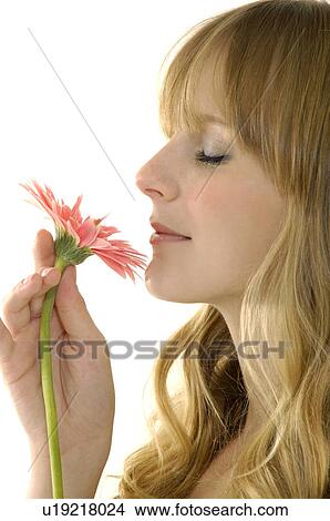 Picture - Side profile of a young woman smelling a flower. Fotosearch