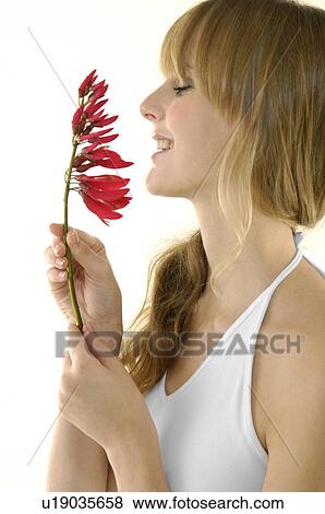 Side profile of a young woman smelling a flower View Large Photo Image Stock Photo - Side profile of a young woman smelling a flower. Fotosearch