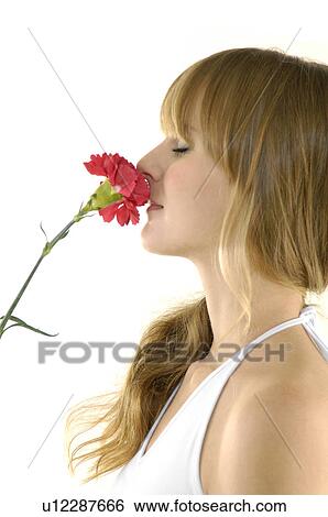 Stock Photograph - Side profile of a young woman smelling a flower. Fotosearch