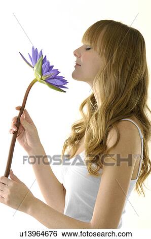 Side profile of a young woman smelling a flower View Large Photo Image Stock Photograph - Side profile of a young woman smelling a flower. Fotosearch