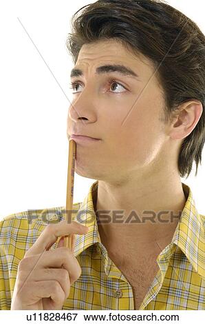 Stock Photo - Close-up of a young man holding a pencil and thinking. Fotosearch