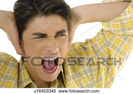 Close-up of a young man shouting with his hands covering his ears View Large Photo Image Stock Photography - Close-up of a young man shouting with his hands covering his ears. Fotosearch