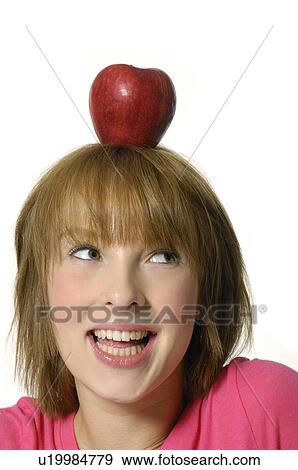 Stock Photo - Close-up of a young woman balancing an apple on her head. Fotosearch