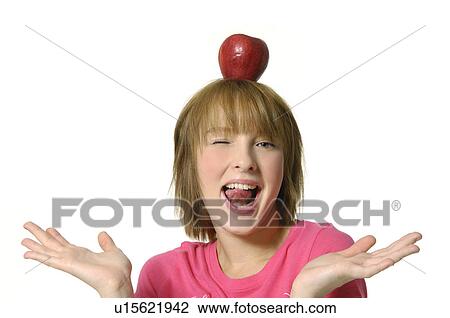 Stock Image - Portrait of a young woman holding an apple on her head and winking. Fotosearch