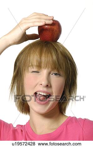 Portrait of a young woman holding an apple on her head View Large Photo Image Stock Photo - Portrait of a young woman holding an apple on her head. Fotosearch