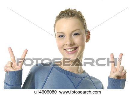 Stock Image - Portrait of a young woman making a peace sign and smiling. Fotosearch