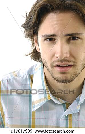 Close-up of a young man looking serious View Large Photo Image Stock Photo - Close-up of a young man looking serious. Fotosearch