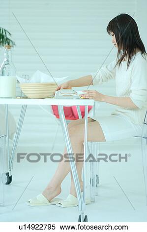 Stock Photography - A young woman at a table in the morning. Fotosearch