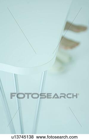 Stock Photo - A young woman's feet under table. Fotosearch