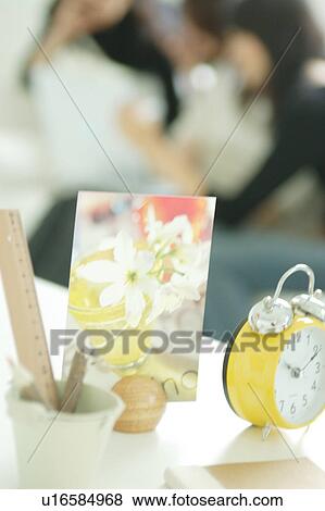 Stock Photo - Clock and postcard with young women in the background. Fotosearch