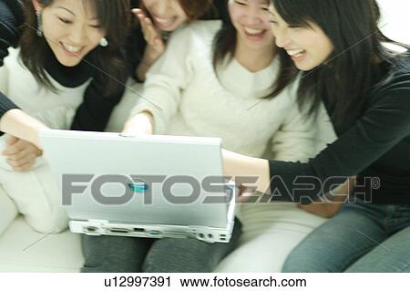 Stock Image - Four young woman looking at computer. Fotosearch